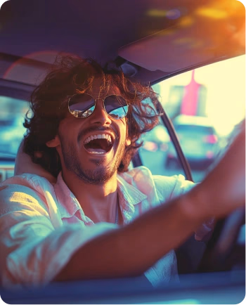 Jeune homme aux cheveux bouclés et lunettes de soleil dans une voiture au coucher du soleil