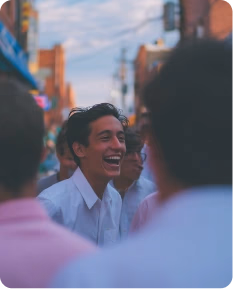 Jeune homme en chemise blanche riant avec des amis dans la rue