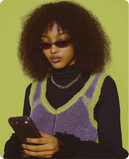 Femme aux cheveux afro et lunettes de soleil consultant son téléphone sur un fond vert clair